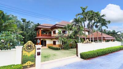 Large two-story house with a gated entrance and lush landscaping