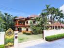 Large two-story house with a gated entrance and lush landscaping