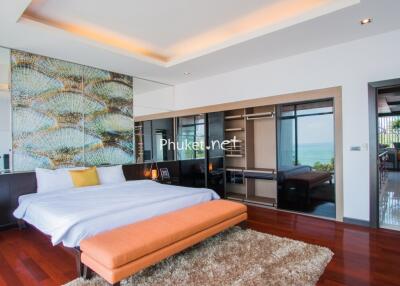 Spacious modern bedroom with wooden flooring, large bed, and a view