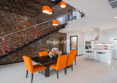 Modern dining area with orange chairs and kitchen in a luxury home