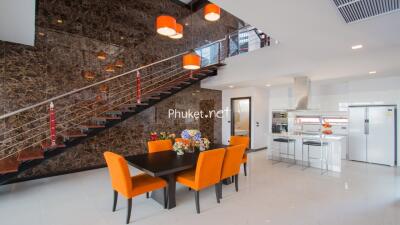 Modern dining area with orange chairs and kitchen in a luxury home