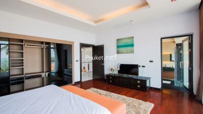 Modern bedroom with wooden flooring, large windows, and en-suite bathroom