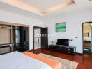 Modern bedroom with wooden flooring, large windows, and en-suite bathroom