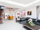 Modern living room with black leather couch, coffee table, and dining area.