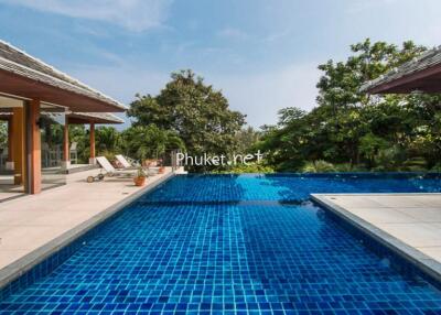 Luxurious outdoor swimming pool area with sun loungers and greenery