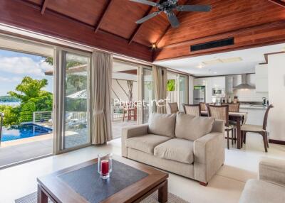 Spacious living area with modern decor, open to kitchen and outdoor pool with scenic view