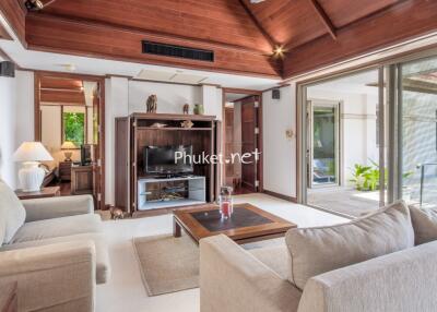 Modern living room with wooden ceiling, comfortable sofas, and large glass doors leading to an outdoor area.