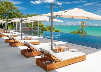 luxurious outdoor pool area with sun loungers and umbrellas overlooking the ocean