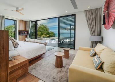 Spacious bedroom with a large bed, sofa, and ocean view through large windows