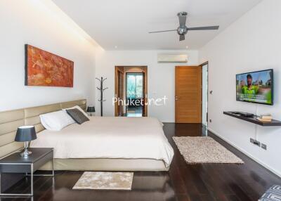 Modern bedroom with wooden flooring, wall art, and a flat screen TV