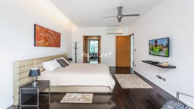 Modern bedroom with wooden flooring, wall art, and a flat screen TV