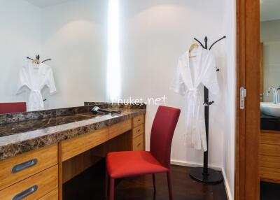 Bright bedroom vanity area with a red chair and wooden dresser