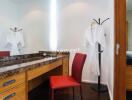 Bright bedroom vanity area with a red chair and wooden dresser