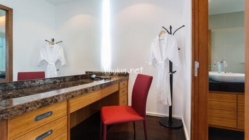 Bright bedroom vanity area with a red chair and wooden dresser