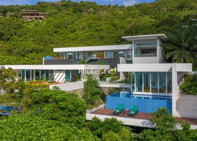 Modern multi-story hillside villa with pool and lush greenery