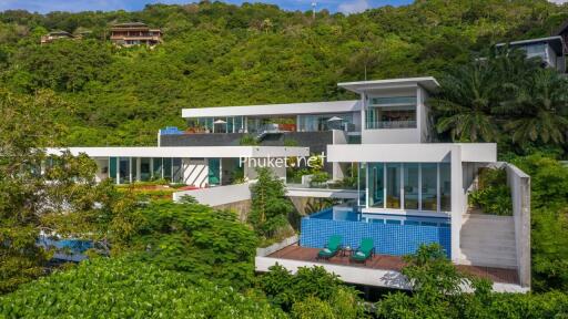 Modern multi-story hillside villa with pool and lush greenery