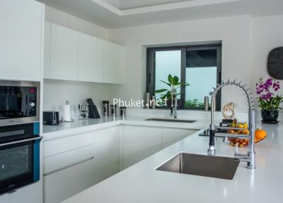 Modern kitchen with white cabinetry, built-in appliances, and a large window