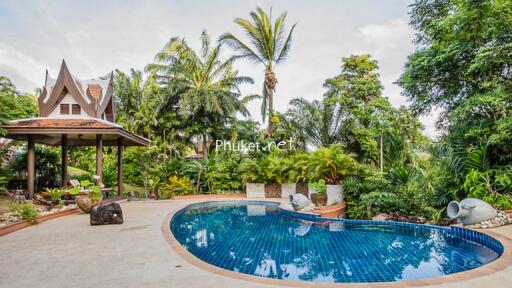 Outdoor pool area with lush landscaping and traditional architecture