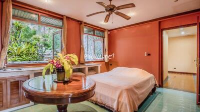 Spacious bedroom with open windows, ceiling fan, and a garden view.