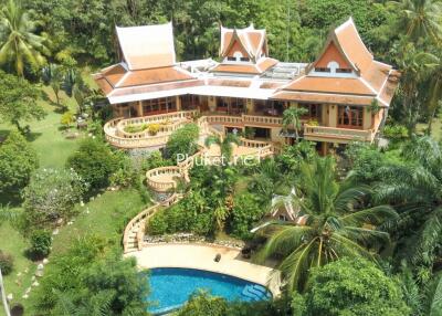 Large Thai-style villa with red roofs, surrounded by lush greenery and a swimming pool