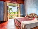 Spacious bedroom with large window overlooking greenery, featuring a wooden bed with intricate headboard and wooden furniture