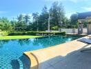 Outdoor swimming pool area with sun loungers and tropical landscaping