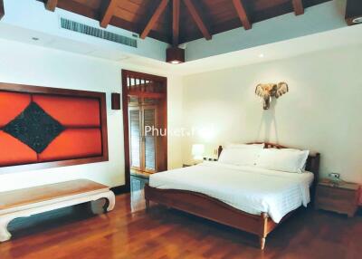 Spacious bedroom with wooden ceiling and cozy decor