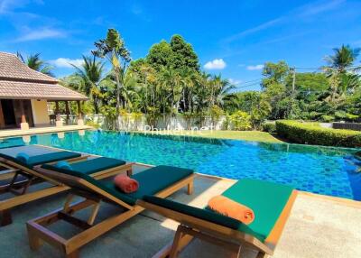 Outdoor pool area with lounge chairs and surrounded by tropical greenery