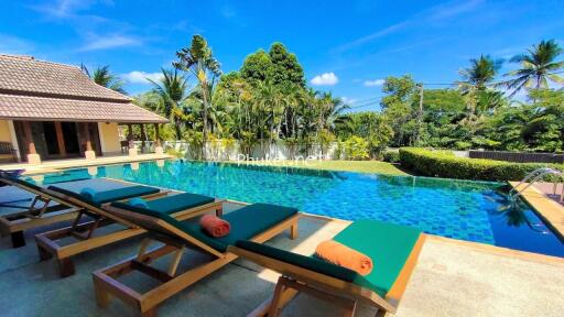 Outdoor pool area with lounge chairs and surrounded by tropical greenery