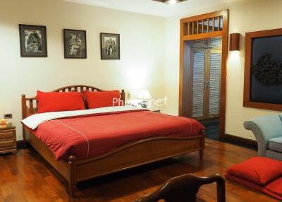 Cozy bedroom with wooden floor and red-themed bedding