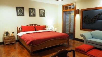 Cozy bedroom with wooden floor and red-themed bedding