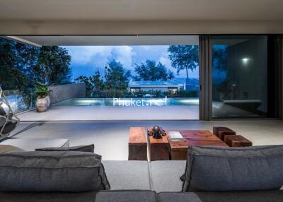 Modern living room with large glass windows overlooking a pool and outdoor area