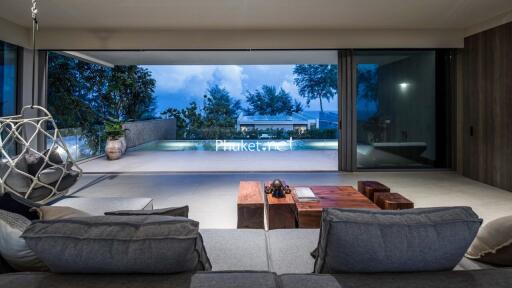 Modern living room with large glass windows overlooking a pool and outdoor area