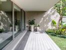 Modern outdoor area with large glass sliding doors, wooden deck, and potted plants