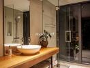 Modern bathroom with glass shower enclosure, wooden vanity, and round sink