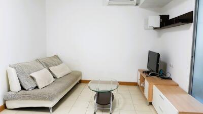 Compact living room with a couch, TV, and glass coffee table