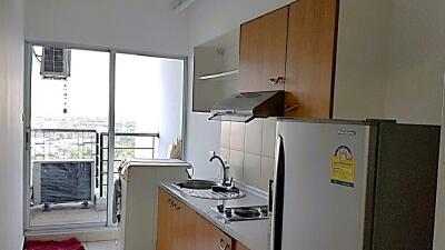 Compact kitchen area with modern appliances and glass door leading to a balcony