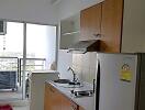 Compact kitchen area with modern appliances and glass door leading to a balcony