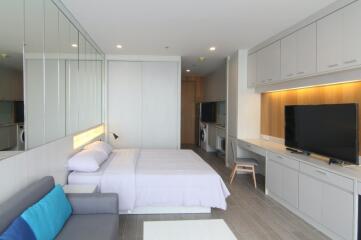 Modern bedroom with integrated workspace and large TV