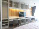 Modern bedroom with open wardrobe cabinets, a wall-mounted TV, and a study area