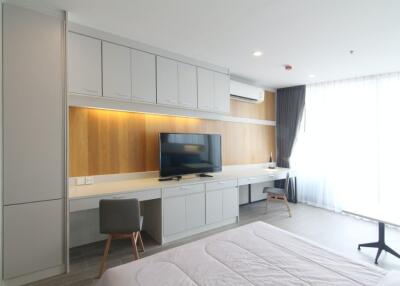 Modern bedroom with built-in cabinetry, TV, and large windows