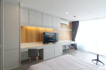 Modern bedroom with built-in cabinetry, TV, and large windows