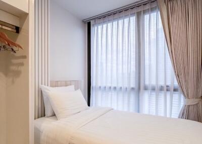 Well-lit modern minimalistic bedroom with sheer curtains and a single bed