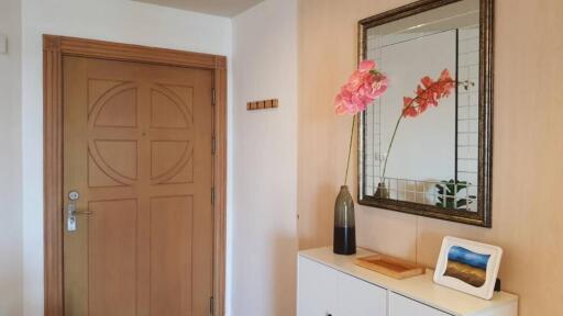 Entrance hallway with a wooden door, mirror, and decor