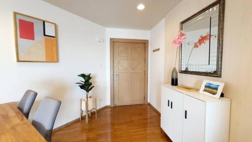 Minimalist entryway with wooden floor, a wall mirror, and decorative items