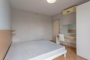 Simple bedroom with bed, desk, chair, and wall-mounted air conditioner