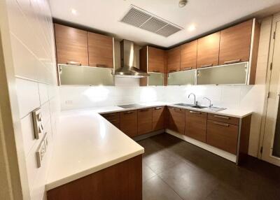 Modern kitchen with wooden cabinets, stainless steel appliances, and white countertops.