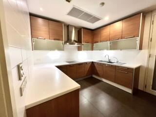 Modern kitchen with wooden cabinets, stainless steel appliances, and white countertops.