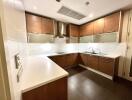 Modern kitchen with wooden cabinets, stainless steel appliances, and white countertops.