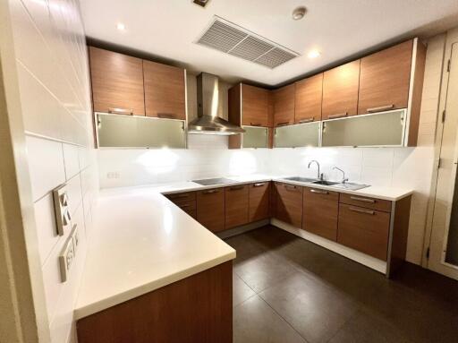 Modern kitchen with wooden cabinets, stainless steel appliances, and white countertops.